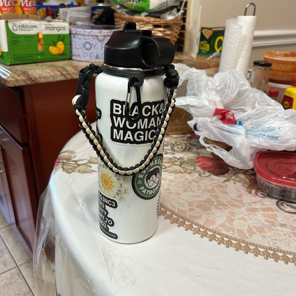 This is a white Hydro flask with a handle on with stickers